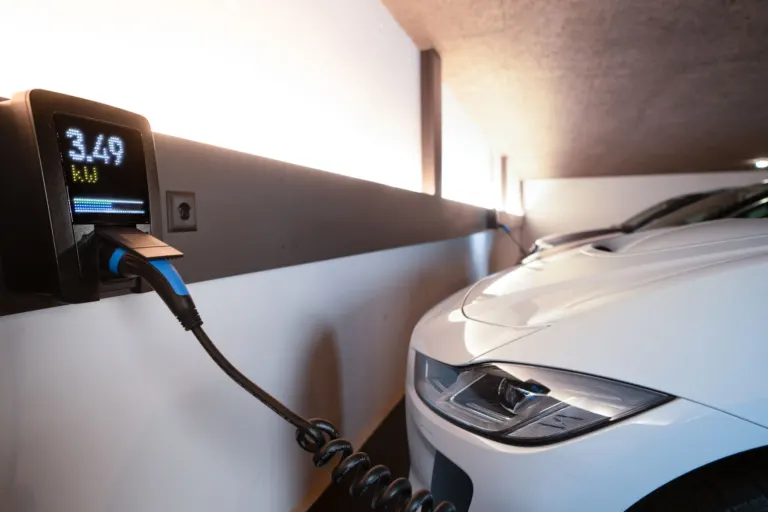 Carro elétrico estacionado numa garagem de prédio com carregador instalado na parede