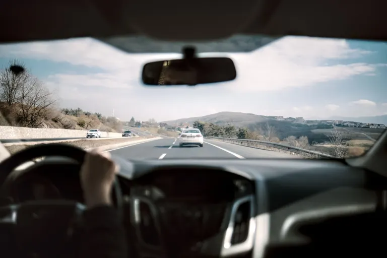 Motorista de aplicativo ao volante de um carro elétrico branco em uma rua de cidade brasileira