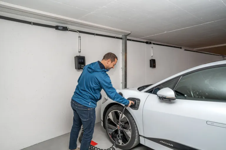 Carro elétrico conectado a um wallbox instalado na garagem de uma casa