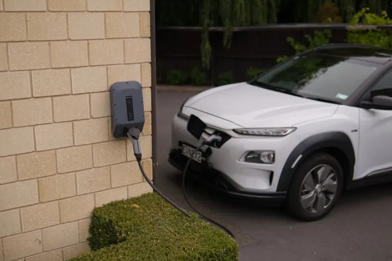Carro elétrico branco estacionado em garagem residencial com carregador de parede instalado